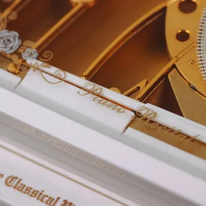 Close-up detail of classical piano music box model with elegant gold and white finish