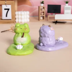 Gros plan de supports de téléphone en résine Zen grenouille et mouton sur un bureau décoré