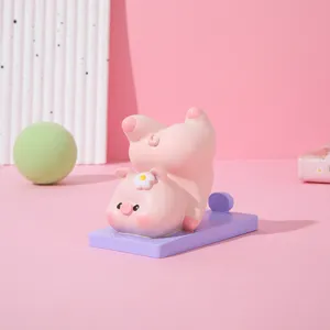 Niedliche rosa Schweinchen-Figur in Yoga-Pose als kreativer Handyhalter für Schreibtisch