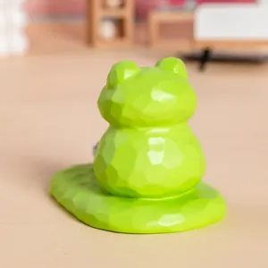Vue arrière d'une jolie figurine de grenouille verte facettée servant de support de téléphone