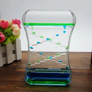 Gros plan sur un sablier liquide bicolore avec des gouttes d'huile vert et bleu