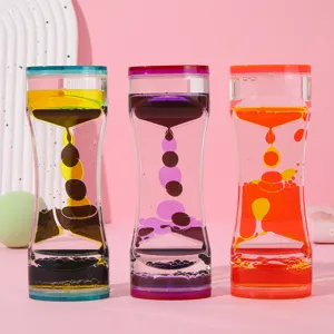 Primer plano de tres relojes de arena de aceite líquido bicolor sobre fondo rosa