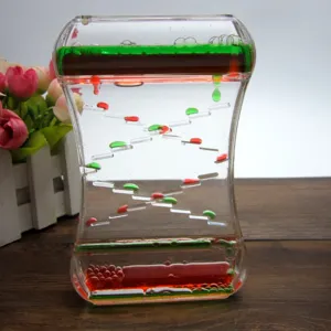 Détail du sablier liquide avec des gouttes d'huile glissantes vertes et rouges anti-stress.