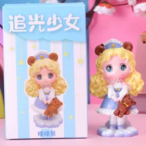 Cute blonde girl figurine holding a teddy bear with its matching blue blind box packaging