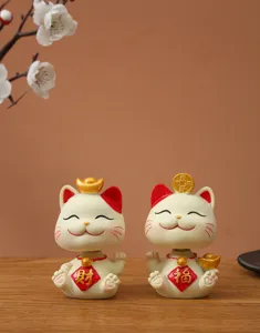 Detailed close-up of two cute Maneki-neko lucky cat ornaments on a wooden table