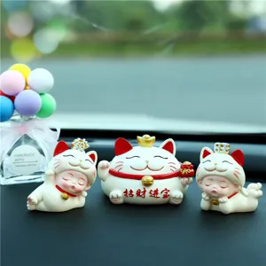 Close-up of cute lucky cat car dashboard ornaments and miniature sleeping kitten figurines