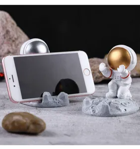 Detalle del creativo soporte para teléfono de astronauta de resina con base lunar