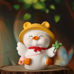 Close-up of a cute white duck figurine with yellow hat and four-leaf clover