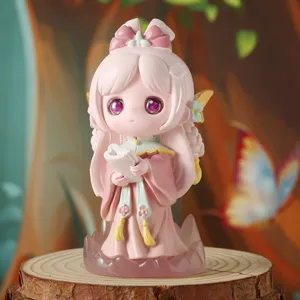 Primo piano di una statuina anime rosa che tiene un rotolo in una foresta calda.