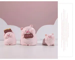Close-up detail of three cute pink resin pig figurines holding lucky message boards for desk decor
