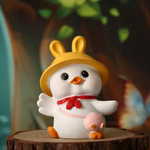 Detailed view of a cute resin duck figurine wearing a yellow bunny hat and red scarf