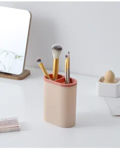 Close-up detail of dual-compartment oval makeup brush and pen holder on clean desk.