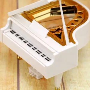 Macro detail of white miniature piano music box showing golden gears and music notes.