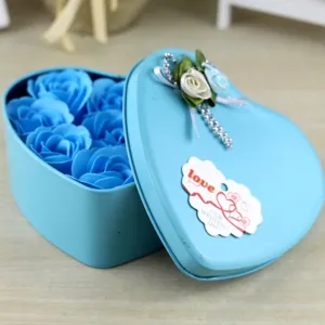 Primo piano di una scatola di latta blu a cuore con nove rose di sapone e tag.