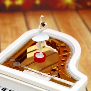 Close-up detail of a white piano music box with a delicate rotating ballerina figurine.