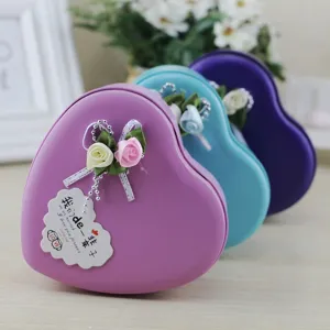 Dettaglio di scatole regalo in latta a forma di cuore con rose e nastri decorativi