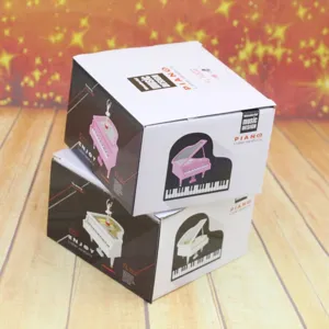 Detailed view showing the packaging for pink and white piano-shaped rotating music boxes