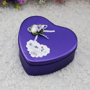 Dettaglio di una scatola regalo in metallo viola a forma di cuore con decorazione.