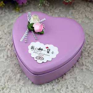 Dettaglio scatola di latta a cuore viola con rosa di raso ed etichetta romantica.