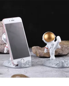 Detalle de figuras de astronautas de resina usadas como soportes para teléfonos móviles