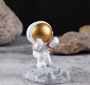 Vista detallada del soporte de teléfono astronauta con visera dorada en base lunar