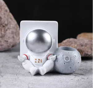 Detalle de una figurita de astronauta de resina blanca y organizador de escritorio de luna
