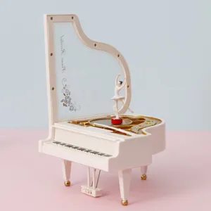 Boîte à musique piano à queue avec ballerine tournante sur fond rose et bleu pastel.