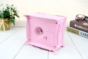 Unterseite einer rosa Vintage-Spieluhr mit Aufziehschlüssel und Batteriefachdeckel.