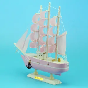 Handcrafted pink wooden sailboat model with pastel fabric sails and metal anchor