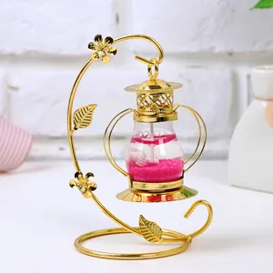 Detalle de un portavelas de hierro dorado con cera de gel rosa y conchas marinas