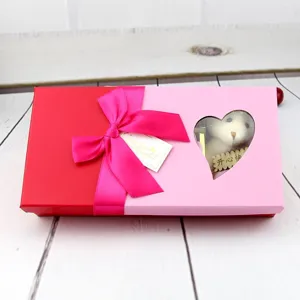 Gros plan sur une boîte cadeau rouge et rose avec fenêtre en cœur, ruban et ours