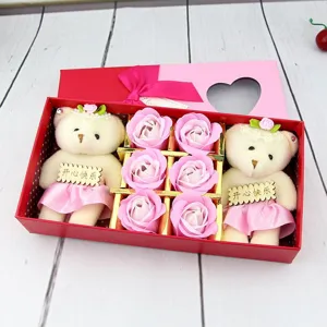 Gros plan d'un coffret cadeau avec deux ours en peluche et six roses de savon roses.
