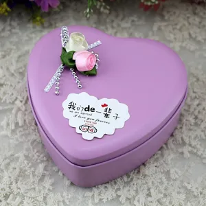 Detailansicht einer lila herzförmigen Geschenkdose aus Blech mit Satinrosen und Schleife