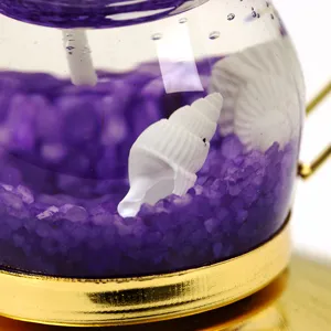 Primer plano de vela de gel con tema océano, arena púrpura y conchas marinas blancas decorativas