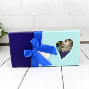 Vue détaillée d'un coffret cadeau bleu avec fenêtre en cœur et petit ours en peluche à l'intérieur