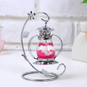 Vista detallada de un candelabro de hierro plateado con una vela de gel rosa y conchas de mar