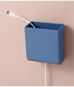 Nahaufnahme des minimalistischen blauen Wand-Aufbewahrungsbox mit einem Ladekabel im Inneren.