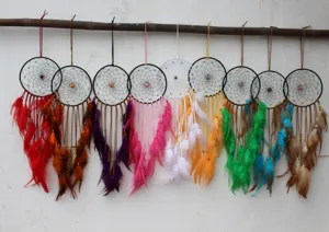 Handgemaakte boho dromenvangers met kleurrijke veren hangend aan een bamboestok.