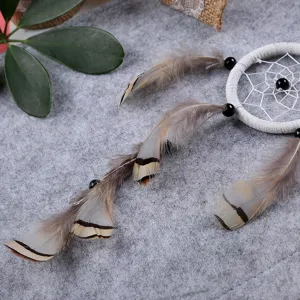 Dettaglio acchiappasogni artigianale in miniatura con anello bianco, perline e piume.