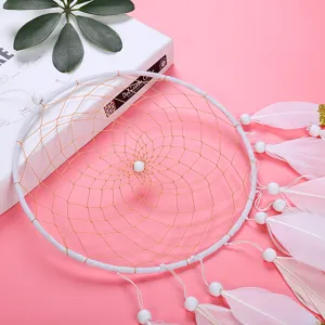 Handmade white dream catcher with pink feathers and beads, perfect for home wall decor.
