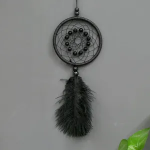 Detalle de atrapasueños negro con red tejida, cuentas negras y decoración de plumas colgantes.