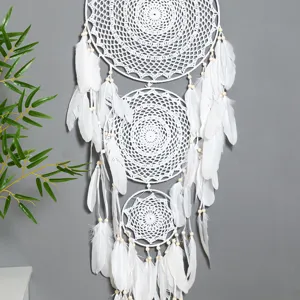 Handmade white crochet dream catcher detail featuring layered circles, feathers, and beads.