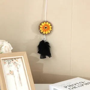 Detailansicht eines Sonnenblumen-Traumfängers mit schwarzen Federn an einer beigen Wand