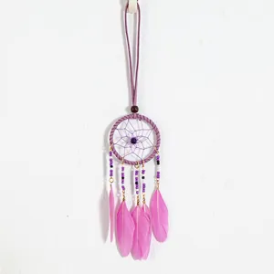 Close-up detail of a handmade purple ethnic dreamcatcher pendant with vibrant pink feathers