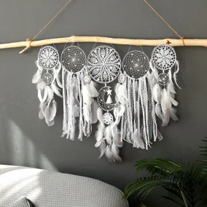 Vue de detail rapprochee d'un attrape-reves blanc en dentelle fait main sur une branche.