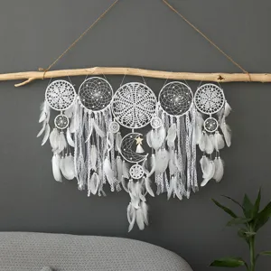 Détail d'attrape-rêves crocheté main, avec plumes blanches et déco murale en branche.
