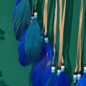 Nahaufnahme von blauen Federn und bunten Perlen an einem handgefertigten Traumfänger Dekor.