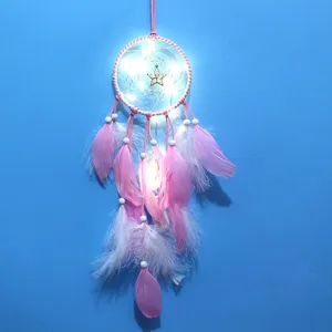 Λεπτομέρεια από ροζ χειροποίητη ονειροπαγίδα με φωτάκια, φτερά και χάντρες για διακόσμηση.