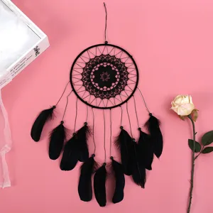 Detailansicht eines schwarzen Traumfängers aus Spitze mit Federn als Wandbehang.