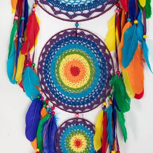 Colorful handmade dream catcher detail view with rainbow crochet web and vibrant feathers.